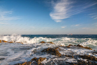 Small boat sails on the wavy sea with beautiful cloud in the sky