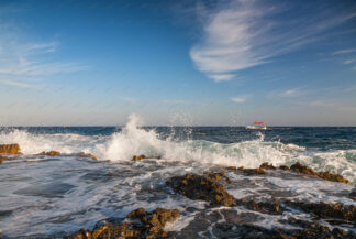 Small boat sails on the wavy sea