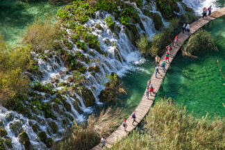 Tourists walk on wooden path in Plitvice National park in Croatia