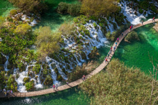 Tourists walk on wooden path in Plitvice National park in Croatia