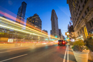 Flatiron building at night on Fifth Avenue with illuminated car trails in New York City