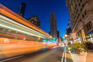 Flatiron building at night on Fifth Avenue with illuminated car trails in New York City