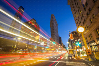 Flatiron building at night on Fifth Avenue with illuminated car trails in New York City