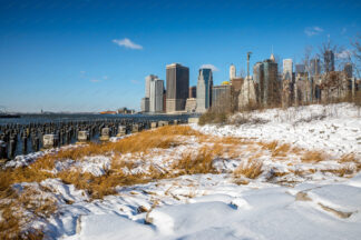 Manhattan downtown over wooden pillars at sunny day in winter, New York City