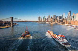 Boats sailing on East river heading to Brooklyn Bridge in New York City