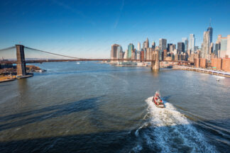 Boat sailing on East river heading to Brooklyn Bridge in New York City